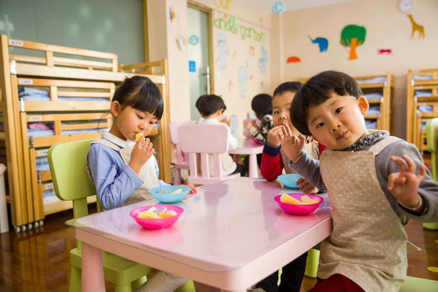 Young children sitting together at a low table, eating fruit