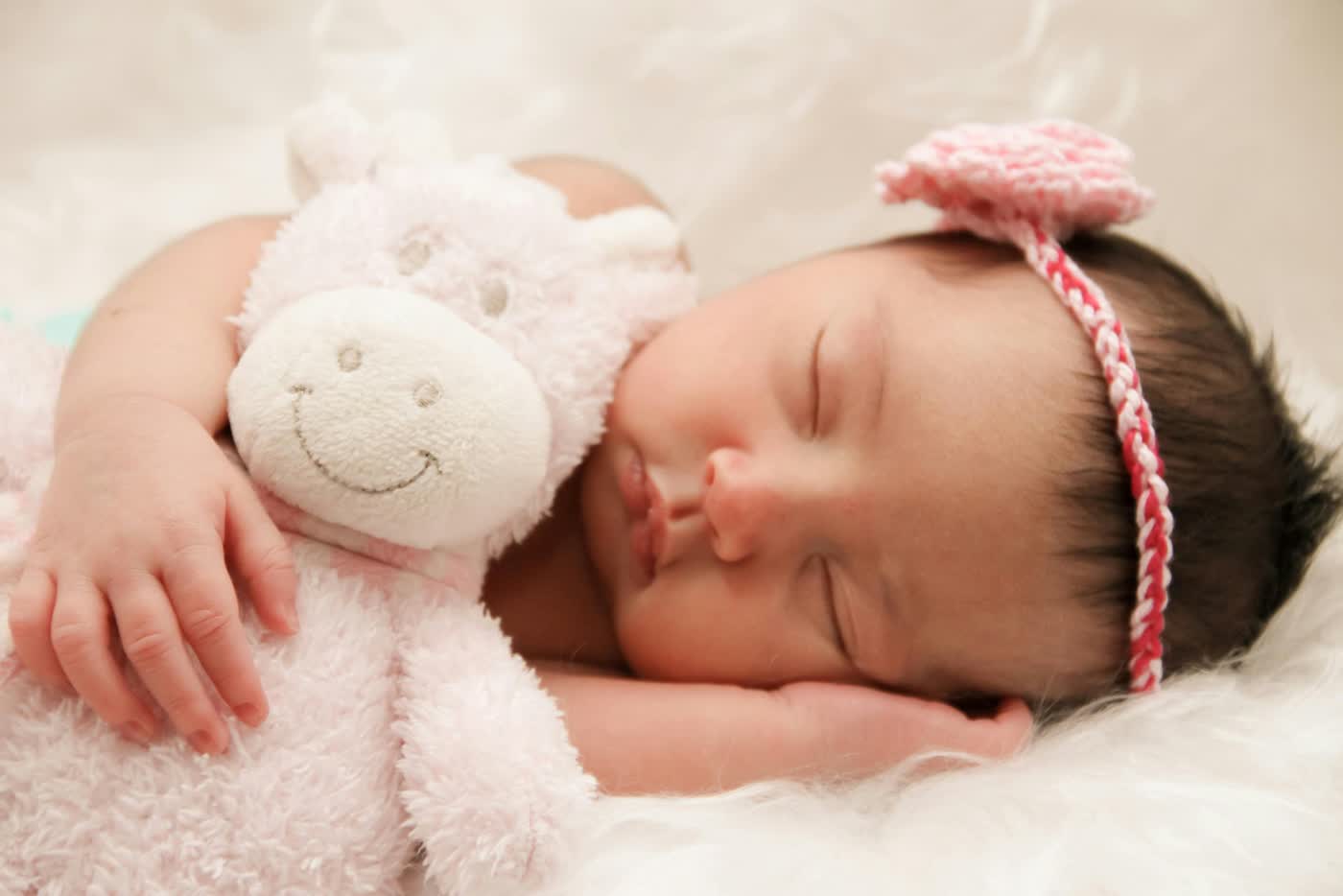 A sleeping newborn cuddling a soft toy